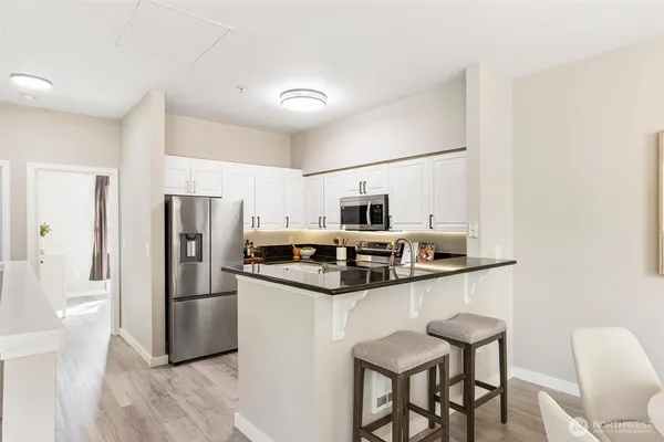 a kitchen with stainless steel appliances a refrigerator a stove a sink and chairs