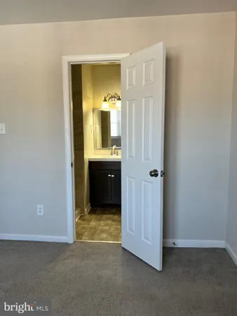 an empty room with mirror and a bathroom