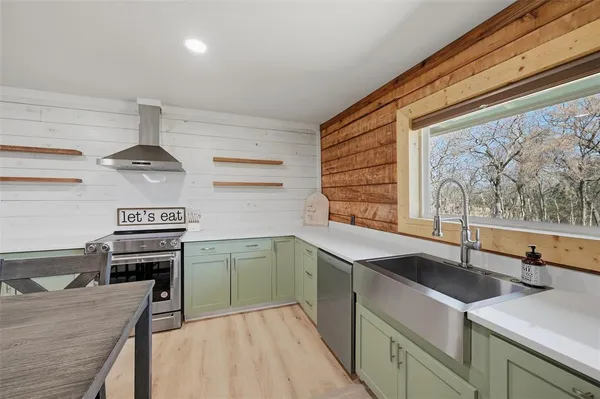 a kitchen with stainless steel appliances kitchen island granite countertop a stove top oven a sink dishwasher a dining table and chairs with wooden floor