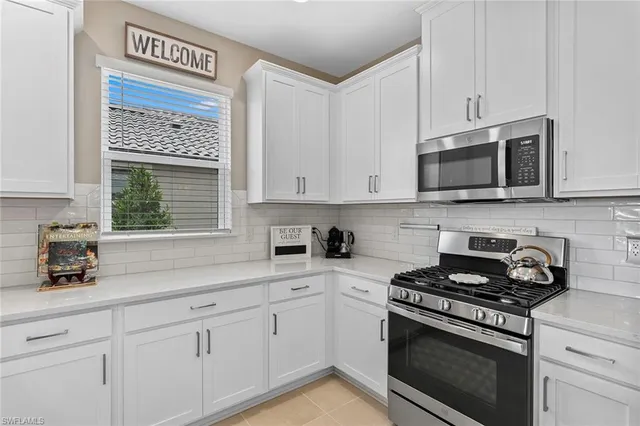 a large white kitchen with a large window and stainless steel appliances