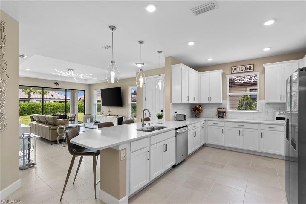 15189 Sacile Court Naples, FL 34114 - Photo 12 of 30 a large white kitchen with a large window and stainless steel appliances