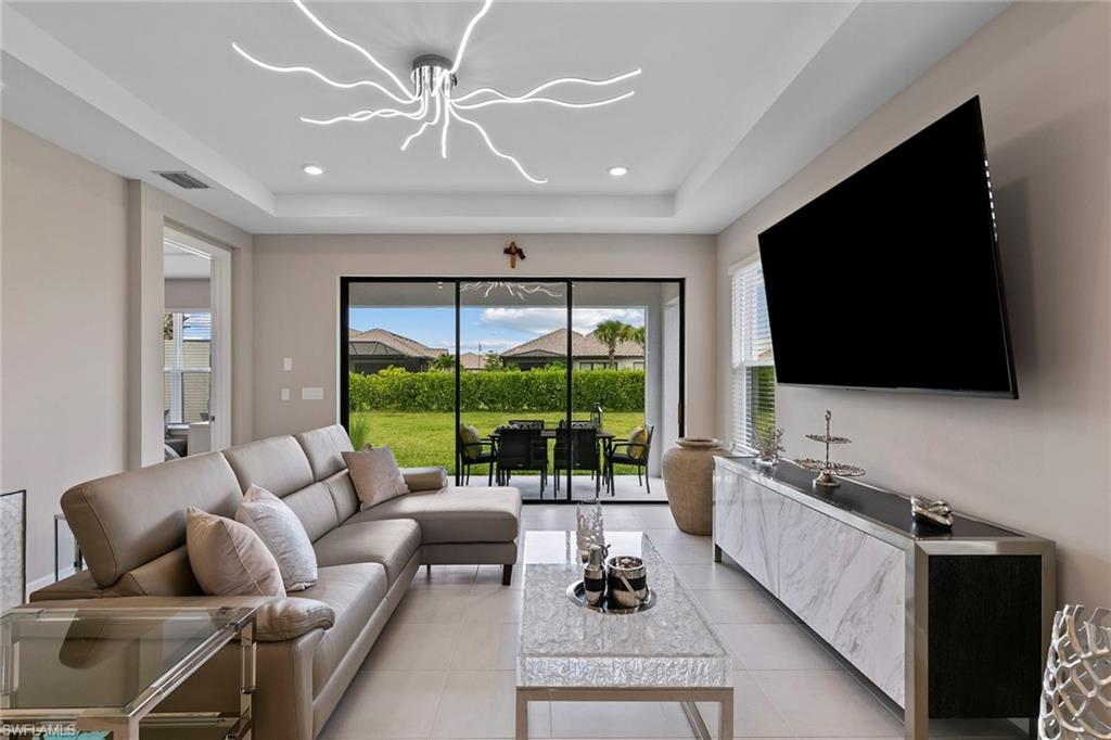 15189 Sacile Court Naples, FL 34114 - Photo 5 of 30 a living room with furniture a flat screen tv and a large window