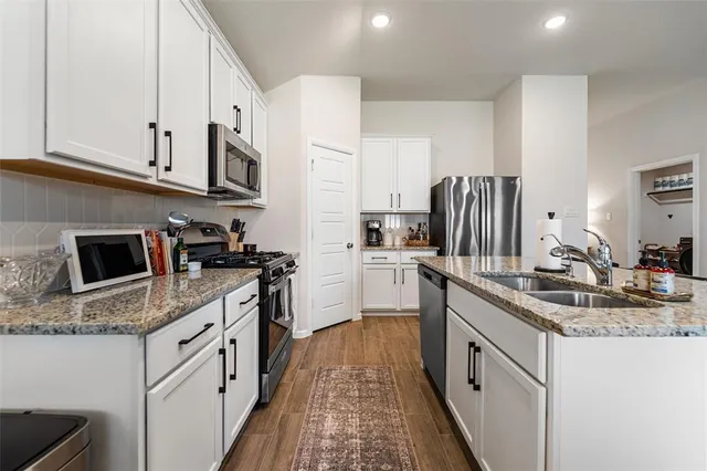 a kitchen with stainless steel appliances granite countertop a sink stove refrigerator and cabinets