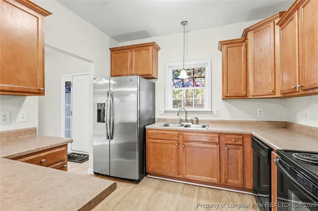 a kitchen with stainless steel appliances granite countertop a refrigerator a sink a stove and white cabinets with wooden floor