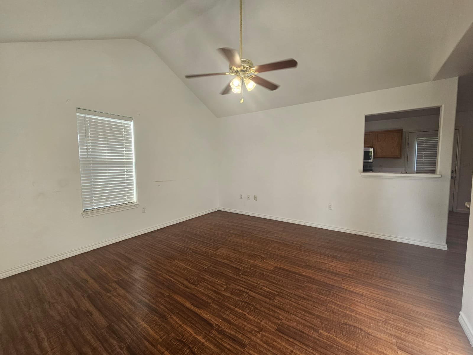 606 Trinity Street Lockhart, TX 78644 - Photo 4 of 23 A well-lit area boasts rich laminate flooring and a peaked ceiling with a ceiling fan.