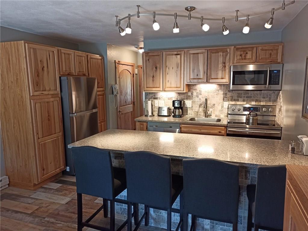 a kitchen with stainless steel appliances granite countertop a sink refrigerator dining table and chairs