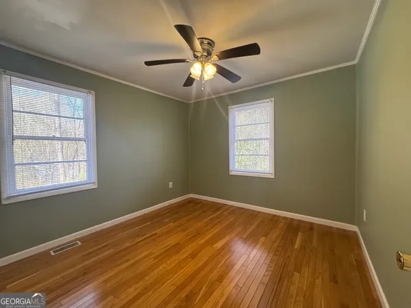 a view of an empty room with wooden floor and a window