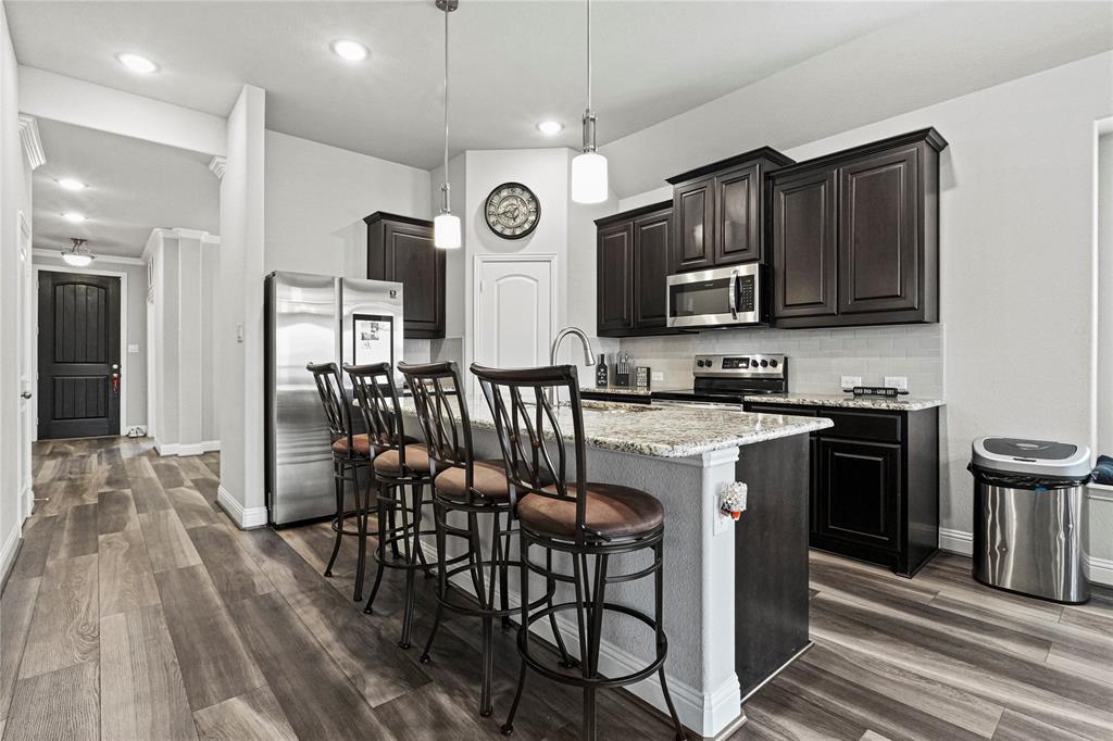 105 Melody Way Red Oak, TX 75154 - Photo 11 of 27 a kitchen with stainless steel appliances granite countertop a stove top oven a sink dishwasher a dining table and chairs with wooden floor