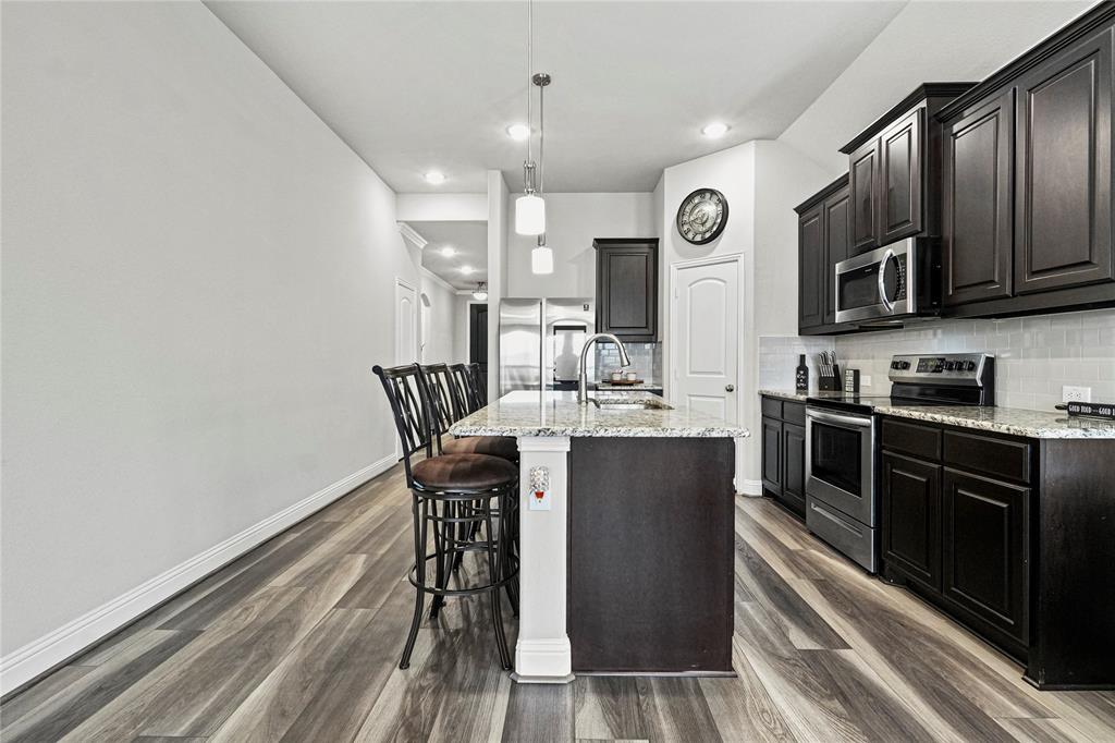 105 Melody Way Red Oak, TX 75154 - Photo 12 of 27 a kitchen with stainless steel appliances granite countertop a stove top oven a sink dishwasher a dining table and chairs with wooden floor