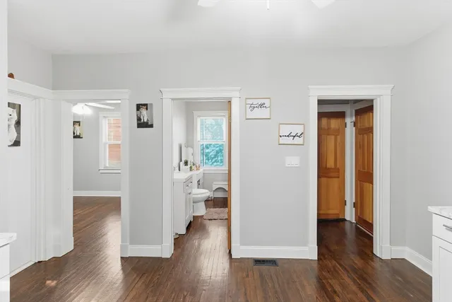 a view of a hallway with wooden floor an empty room and a living room