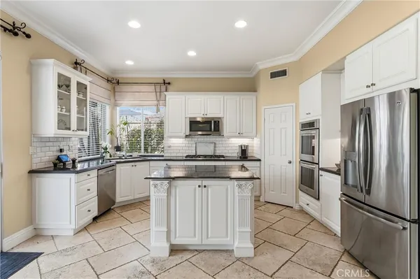 a kitchen with granite countertop a refrigerator stove top oven and sink