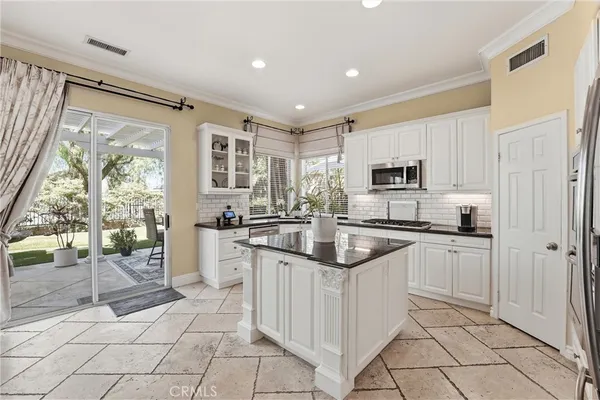 a kitchen with white cabinets a sink a window and stainless steel appliances