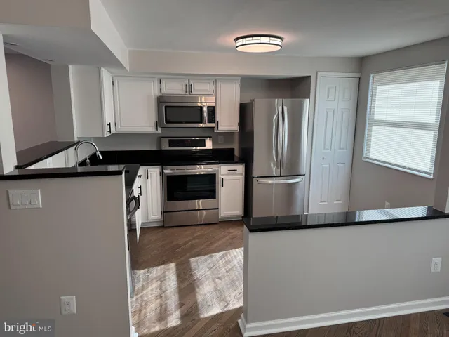 a kitchen with stainless steel appliances granite countertop a refrigerator a stove a sink and a microwave