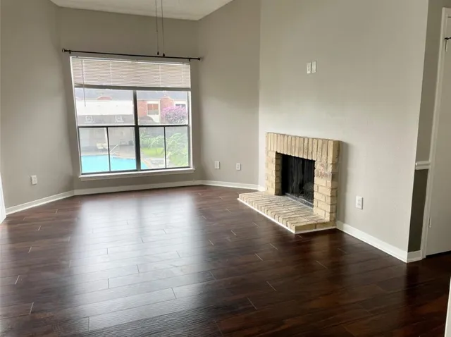 an empty room with wooden floor and fireplace
