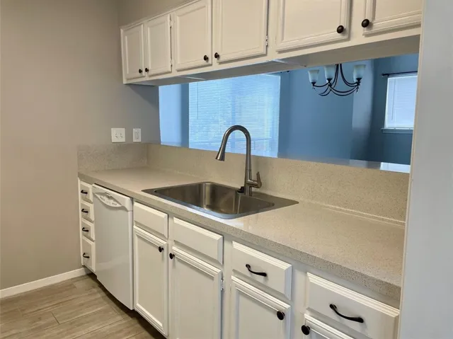 a kitchen with white cabinets and sink