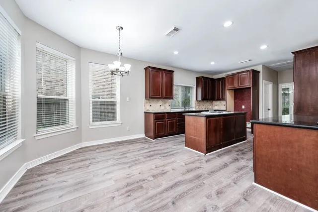 a kitchen with stainless steel appliances granite countertop a stove top oven a sink dishwasher a refrigerator and a oven with wooden floor