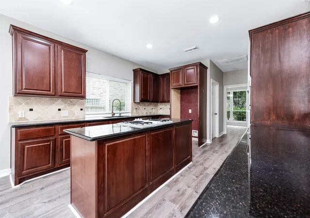 a kitchen with stainless steel appliances granite countertop wooden cabinets a stove top oven a sink and dishwasher