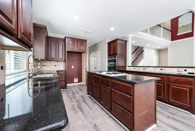 a kitchen with stainless steel appliances granite countertop a stove a sink and a microwave