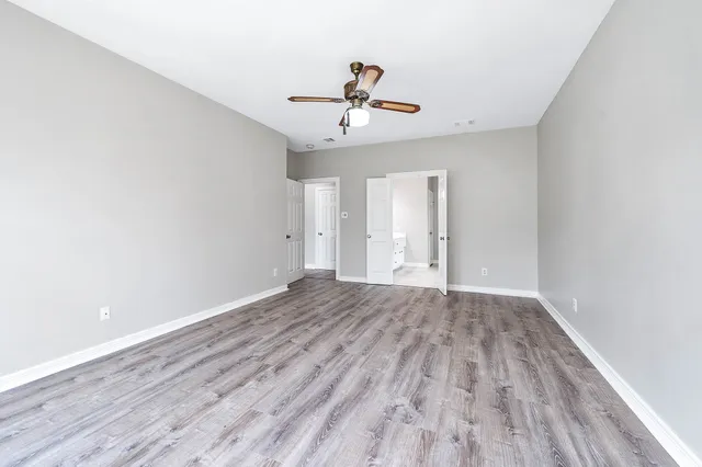 an empty room with wooden floor ceiling fan and window