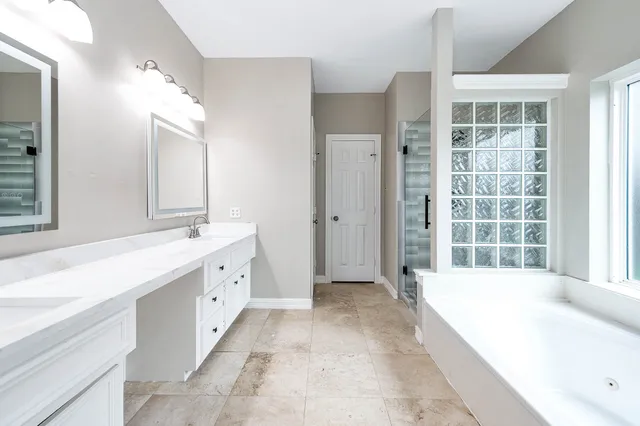 a spacious bathroom with a tub sink and mirror
