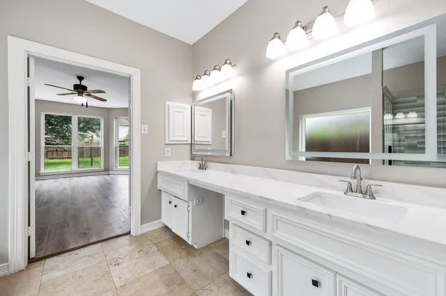 a bathroom with a double vanity sink mirror and next to a window