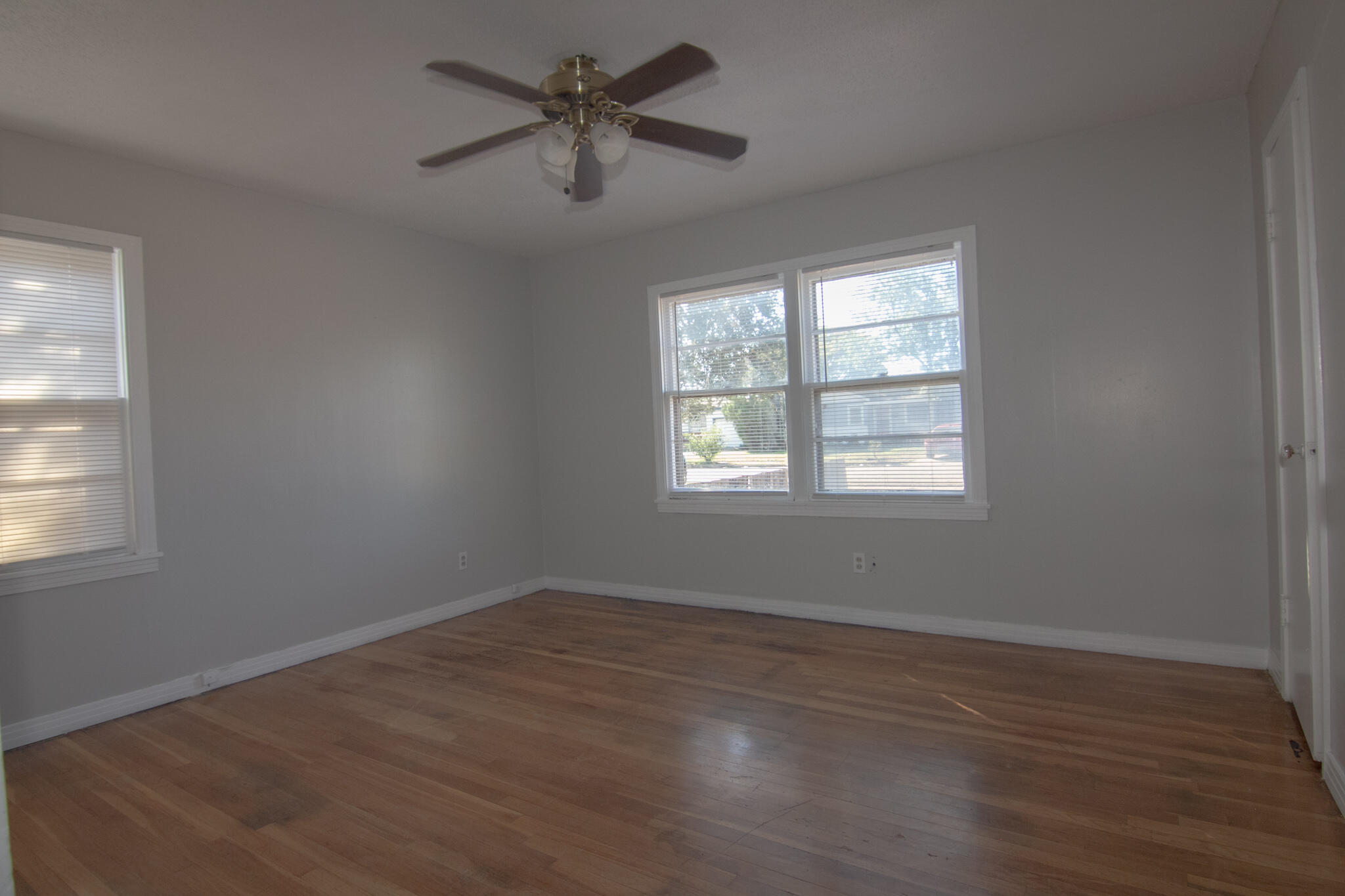 8707 11th Street Lubbock, TX 79416 - Photo 6 of 9 an empty room with wooden floor ceiling fan and windows