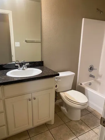 a bathroom with a granite countertop toilet sink and mirror