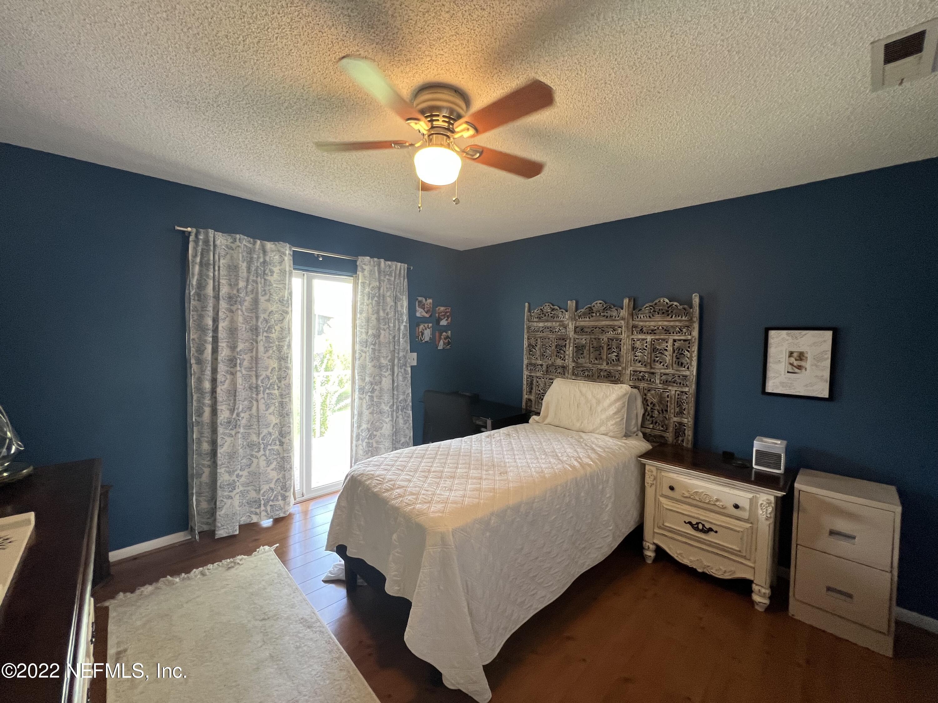 7122 Cypress Cove Road, Unit 47 Jacksonville, FL 32244 - Photo 21 of 24 a bedroom with a bed and a chandelier