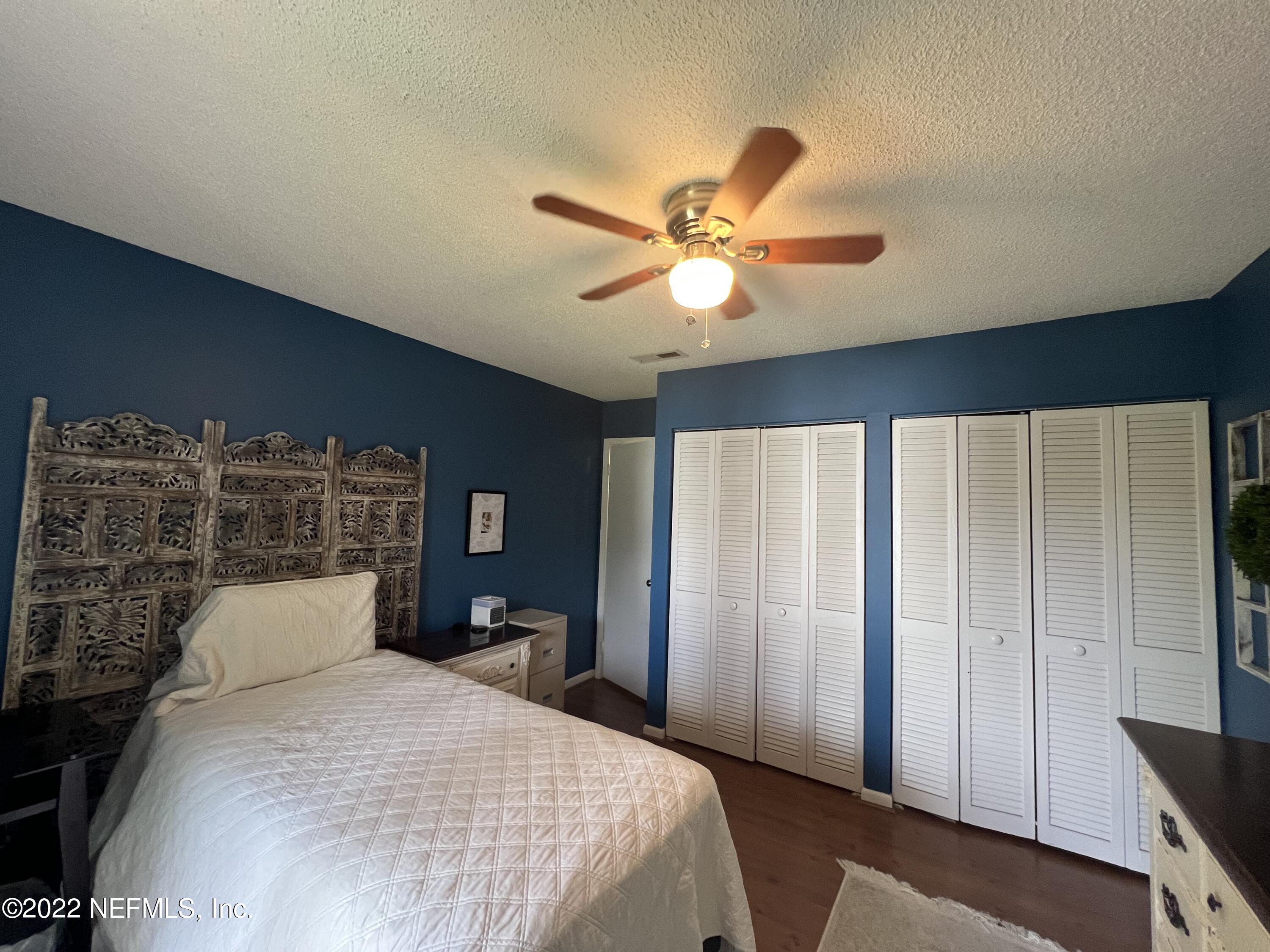 7122 Cypress Cove Road, Unit 47 Jacksonville, FL 32244 - Photo 22 of 24 a bedroom with a large bed and a chandelier