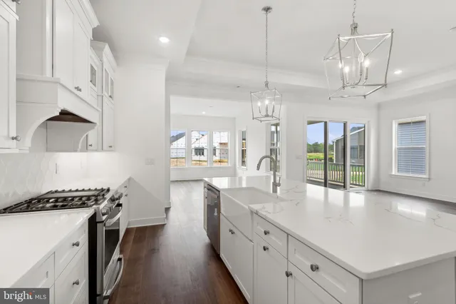 a kitchen with stainless steel appliances a stove a sink a center island and wooden floor