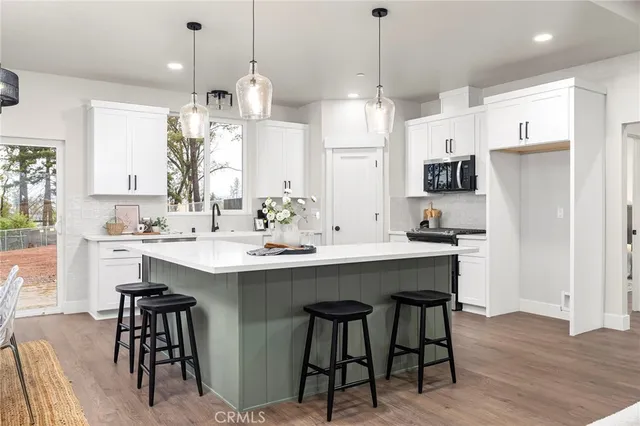 a kitchen with stainless steel appliances a dining table chairs refrigerator and sink