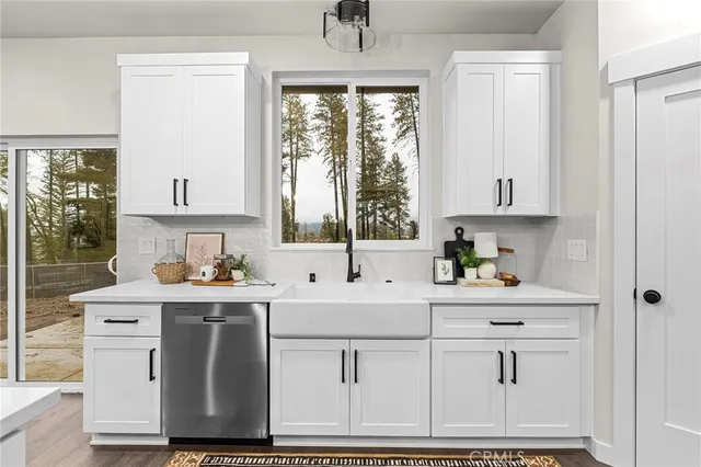 a kitchen with white cabinets and window