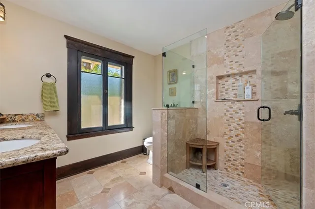 a bathroom with a granite countertop sink a mirror and shower