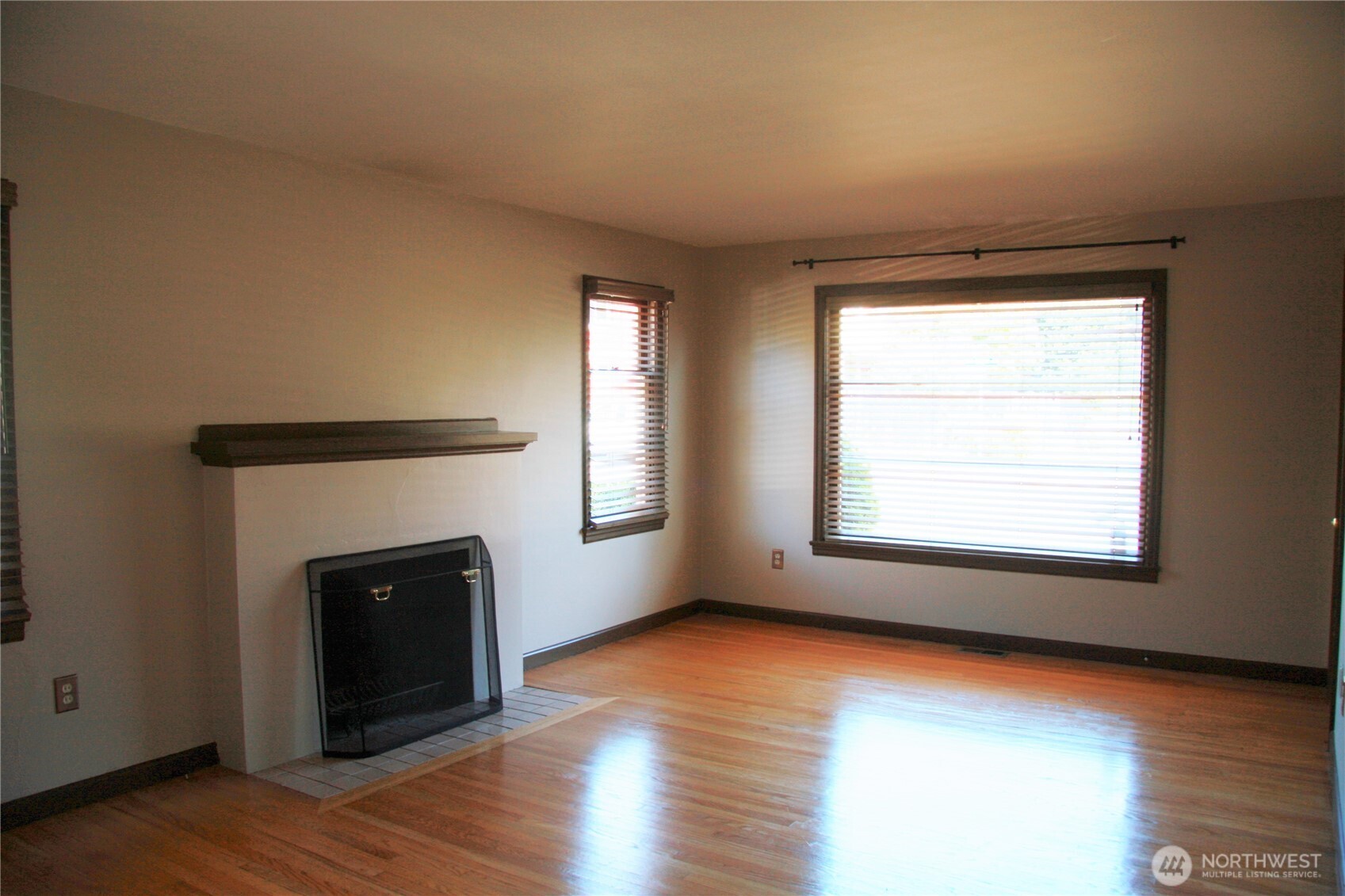2213 Northwest 65th Street Seattle, WA 98117 - Photo 3 of 11 an empty room with wooden floor a fireplace and windows