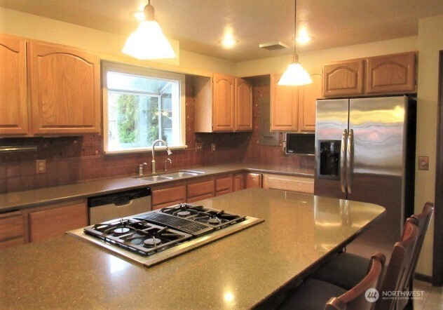 2213 Northwest 65th Street Seattle, WA 98117 - Photo 5 of 11 a kitchen with stainless steel appliances granite countertop a sink a stove and a refrigerator