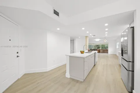 a living room with stainless steel appliances kitchen island hardwood floor and a sink