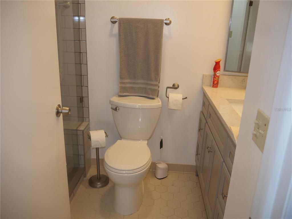 6165 Chesham Drive, Unit 5 New Port Richey, FL 34653 - Photo 17 of 35 a white toilet sitting next to a bathroom sink and a shower