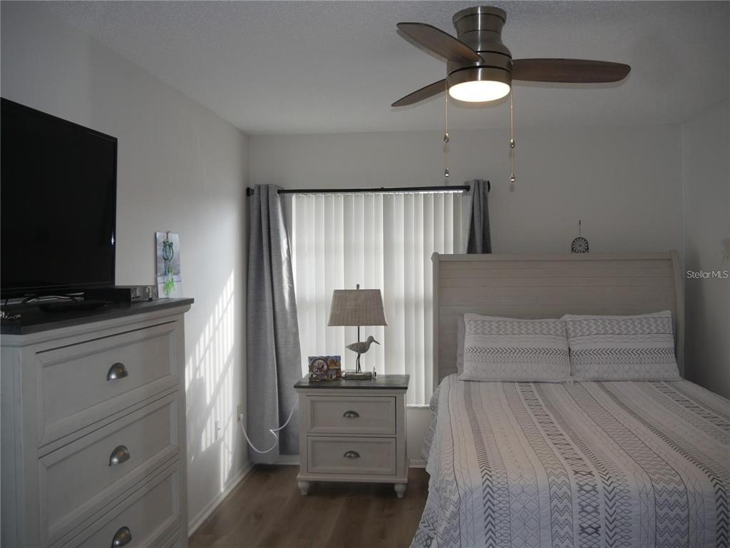 6165 Chesham Drive, Unit 5 New Port Richey, FL 34653 - Photo 23 of 35 a bedroom with a bed and a flat tv screen on dresser