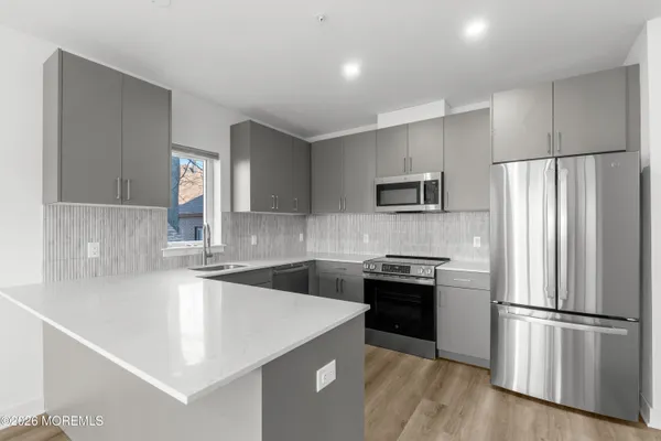 a large kitchen with a sink and dishwasher a refrigerator with wooden cabinets