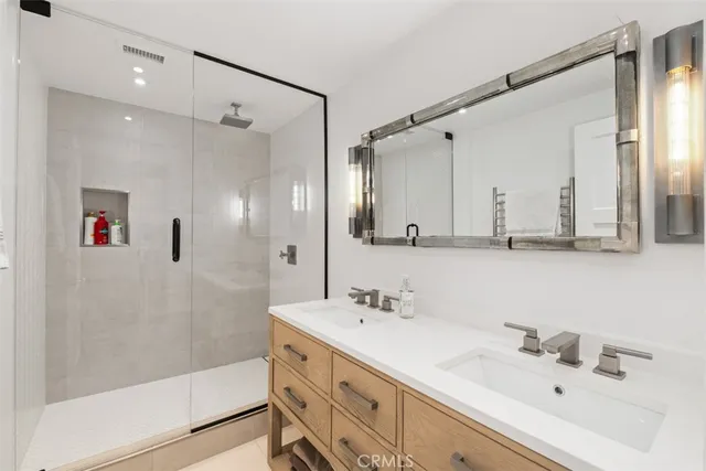 a bathroom with a double vanity sink mirror and shower