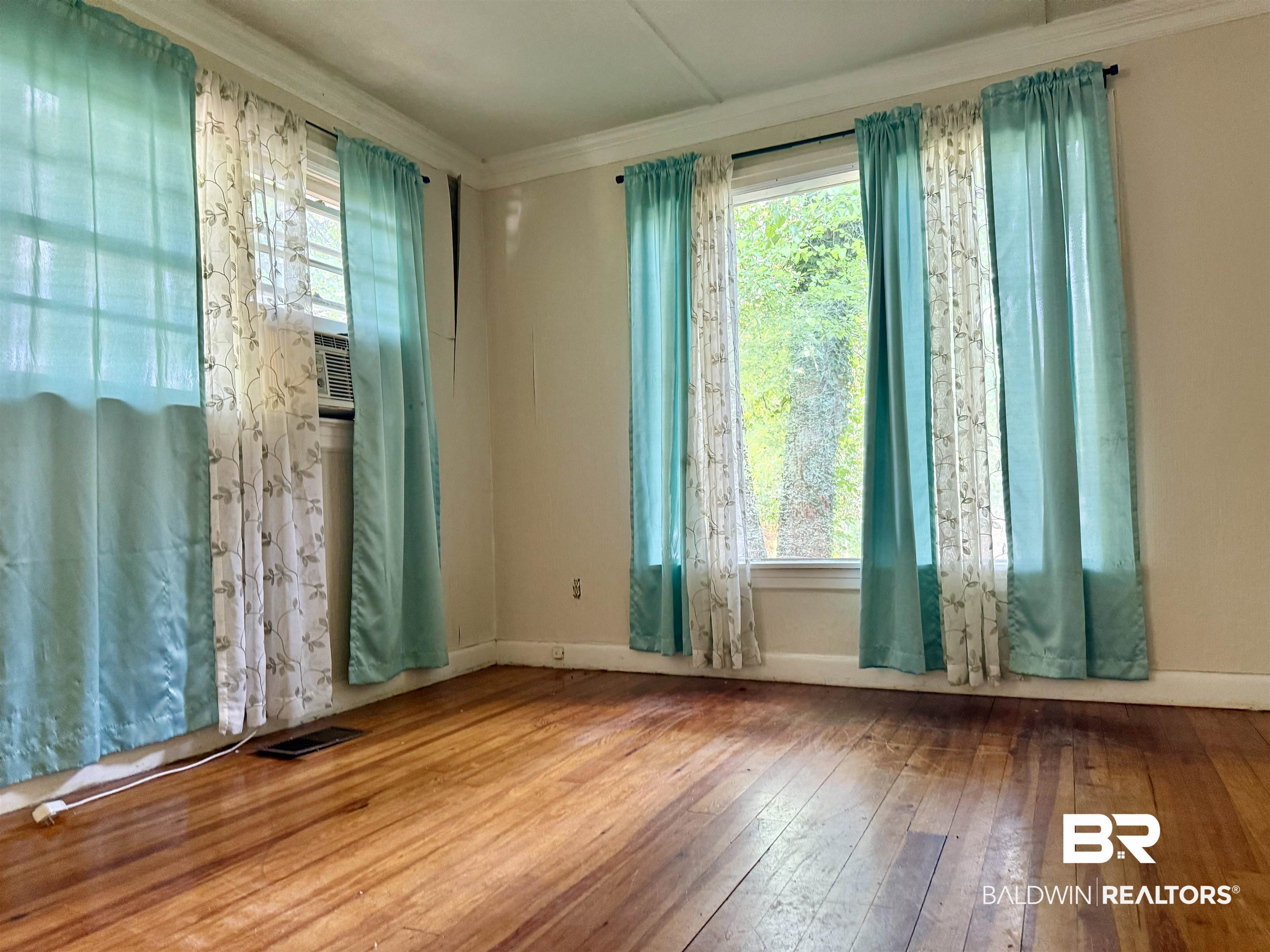610 Alco Drive Brewton, AL 36426 - Photo 14 of 18 Empty room featuring ornamental molding, hardwood / wood-style floors, healthy amount of natural light, and baseboards