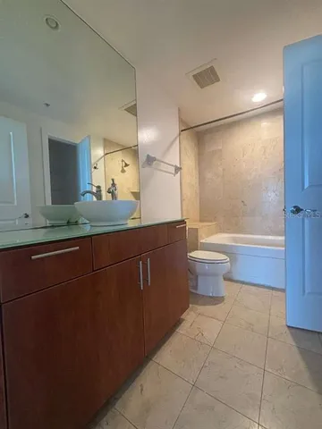 a bathroom with a granite countertop sink a toilet a mirror and shower