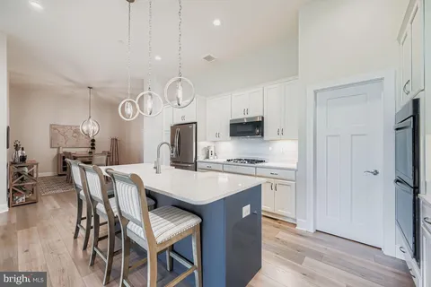a kitchen with stainless steel appliances a table chairs stove and cabinets