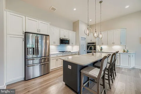 a kitchen with stainless steel appliances a stove a sink a refrigerator a center island a table and chairs