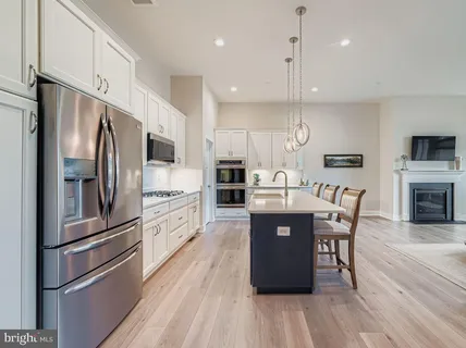 a kitchen with stainless steel appliances granite countertop a refrigerator a stove top oven a sink dishwasher a dining table and chairs cabinets with wooden floor