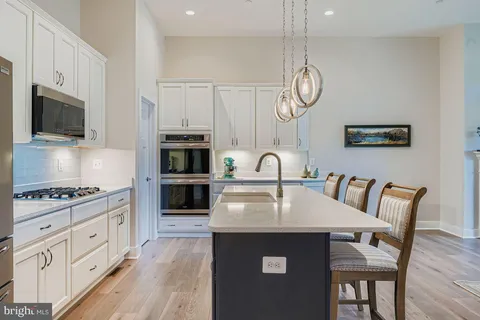 a kitchen with stainless steel appliances granite countertop a stove a microwave a sink a dining table and chairs