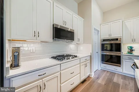 a kitchen with cabinets stainless steel appliances and wooden floor