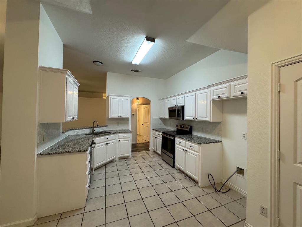6611 Rockdale Road Fort Worth, TX 76134 - Photo 9 of 32 a kitchen with white cabinets a sink stove and refrigerator