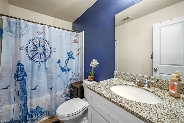 a bathroom with a granite countertop sink toilet and shower