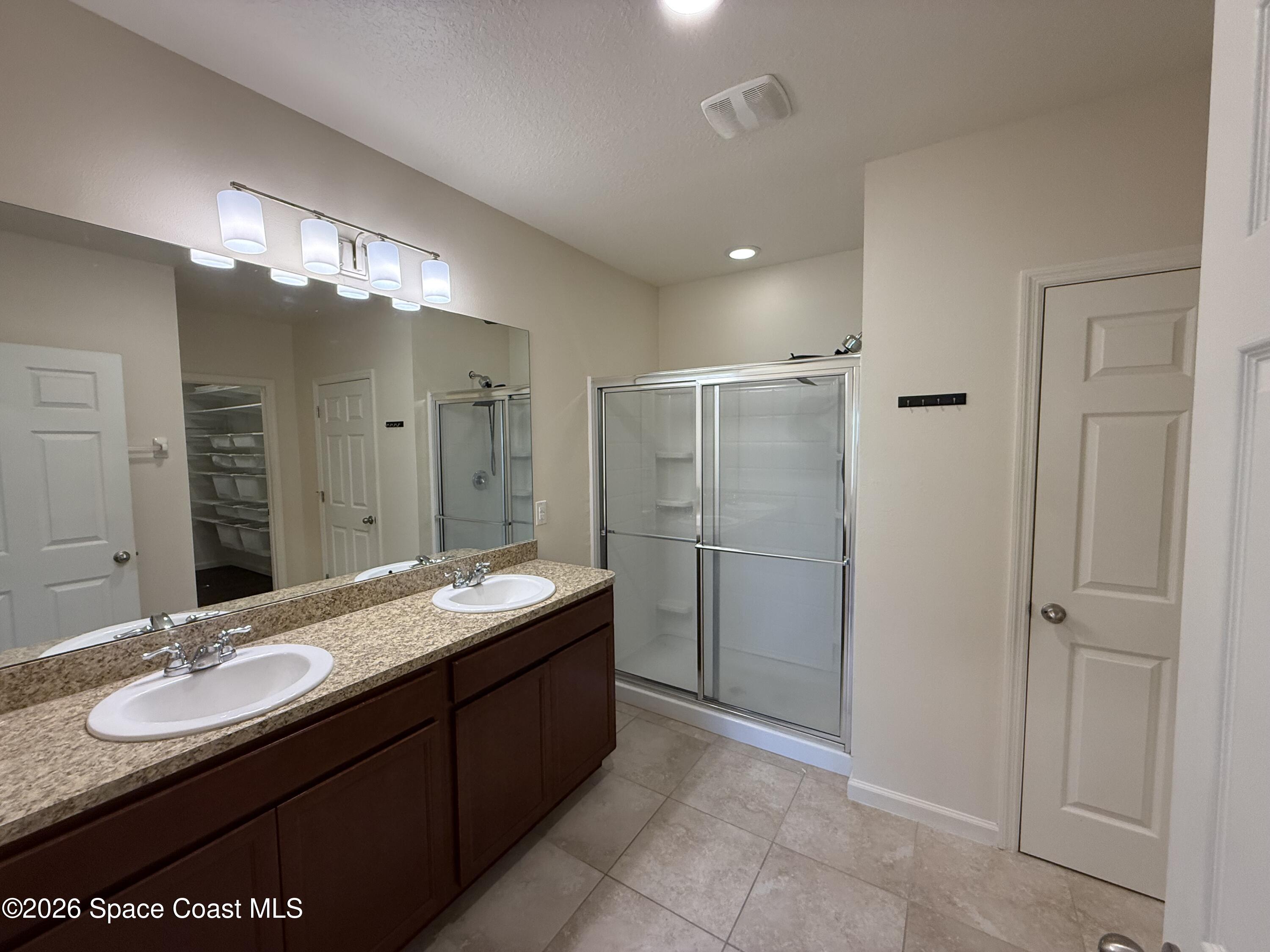 1070 Swiss Pointe Lane Rockledge, FL 32955 - Photo 15 of 18 a bathroom with a granite countertop sink a large mirror and a shower